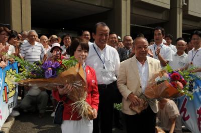市役所正面玄関前で、来庁した三宅宏実選手と三宅義行さんに、須田健治市長が花束贈呈した時の写真です。