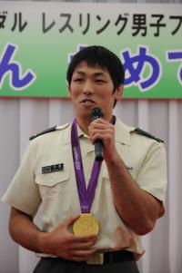米満達弘選手が凱旋報告をしている場面の写真です。