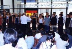 市民ホールで合唱を披露するシンケル高校合唱団の写真